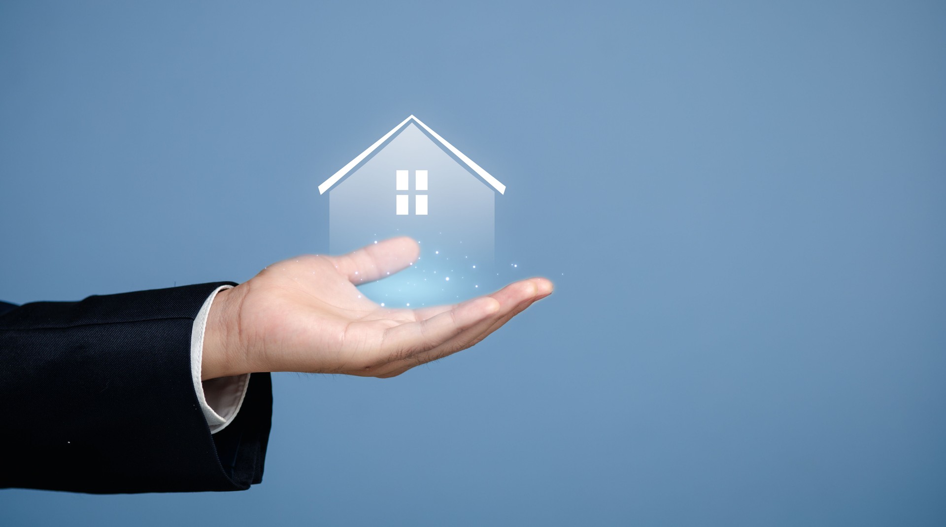 Hand Holding 3D House Icon Against Soft Blue Background